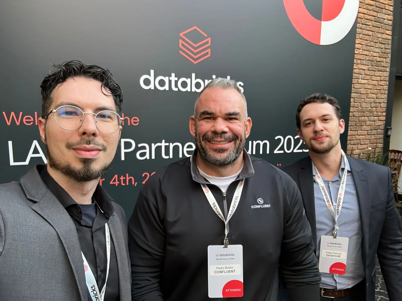 Selfie of three people in front of the Databricks LATAM Partner Summit backdrop