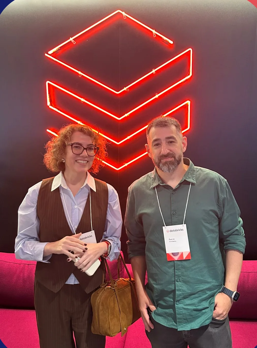 Two people in front of the Databricks neon logo at a 2024 event