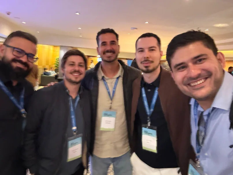 Five people wearing badges smiling for a photo at a 2025 event